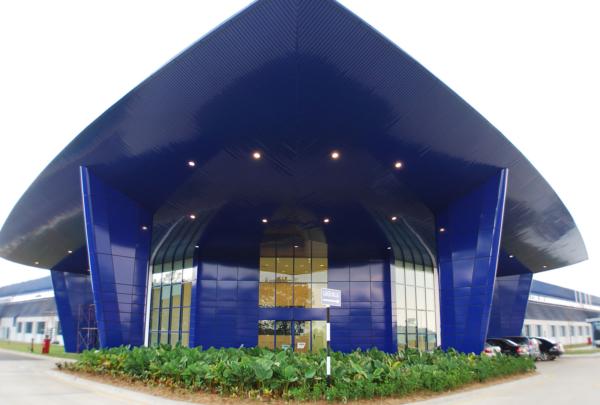 Exterior entrance of Spirit AeroSystems SE Asia. Bright blue airfoil inspired triangular building.